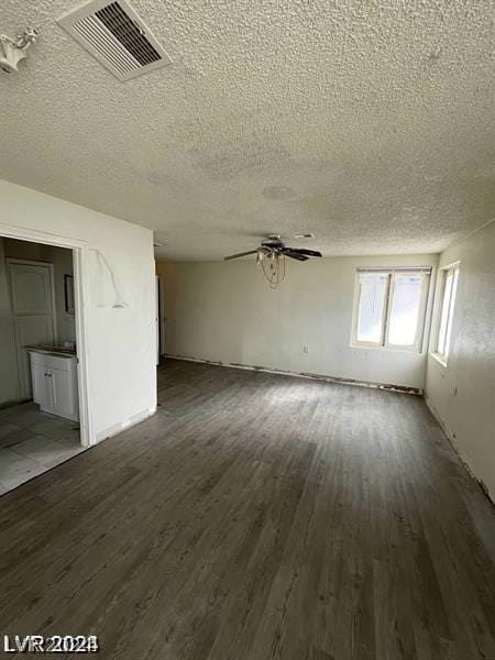 unfurnished living room featuring ceiling fan, a textured ceiling, and dark hardwood / wood-style flooring