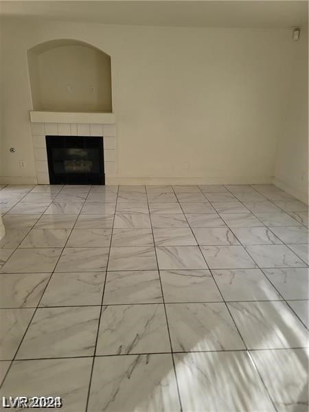 unfurnished living room with light tile patterned flooring and a tile fireplace