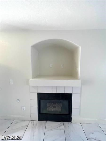 interior details featuring a tiled fireplace and tile patterned floors