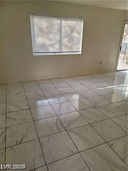 unfurnished room with light tile patterned flooring and plenty of natural light