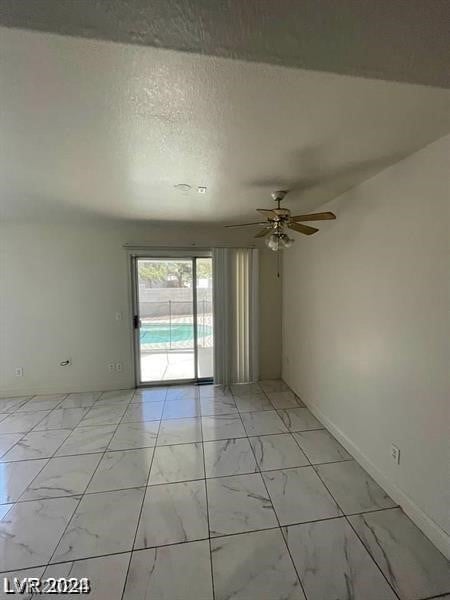 tiled empty room featuring a textured ceiling and ceiling fan