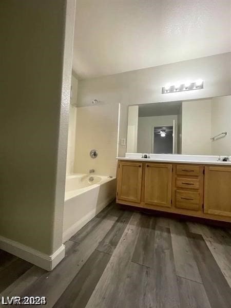 bathroom featuring dual vanity, hardwood / wood-style floors, and a bathtub