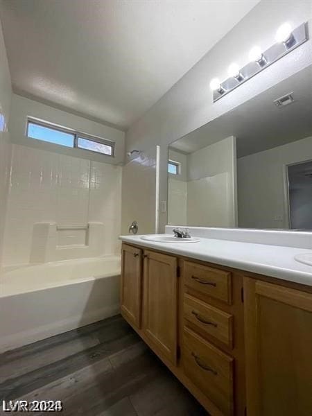 bathroom with dual bowl vanity, hardwood / wood-style flooring, and washtub / shower combination