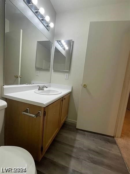 bathroom with hardwood / wood-style floors, vanity, and toilet