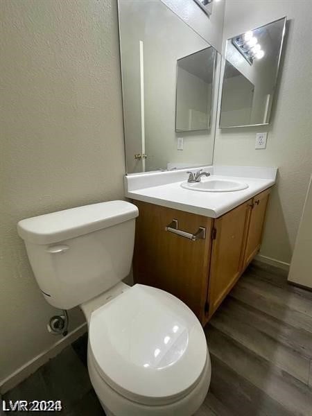 bathroom featuring vanity, wood-type flooring, and toilet