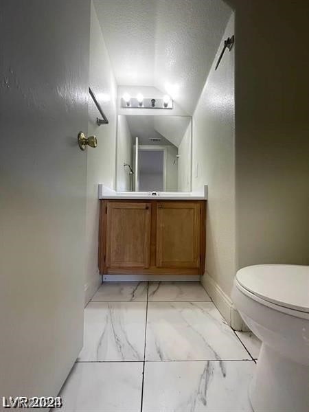 bathroom with a textured ceiling, toilet, vanity, and lofted ceiling