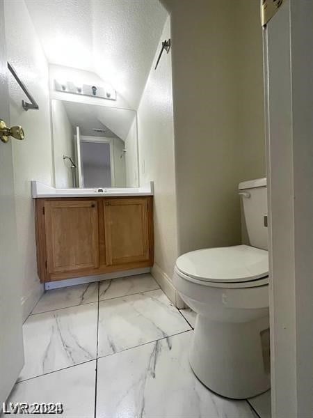 bathroom with tile patterned flooring, lofted ceiling, toilet, and vanity