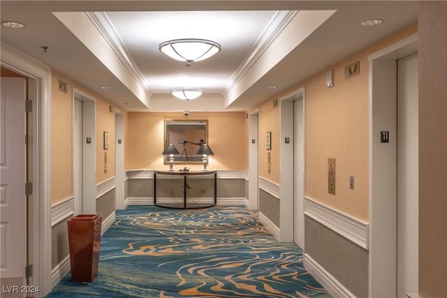 corridor featuring ornamental molding, dark carpet, a raised ceiling, and elevator