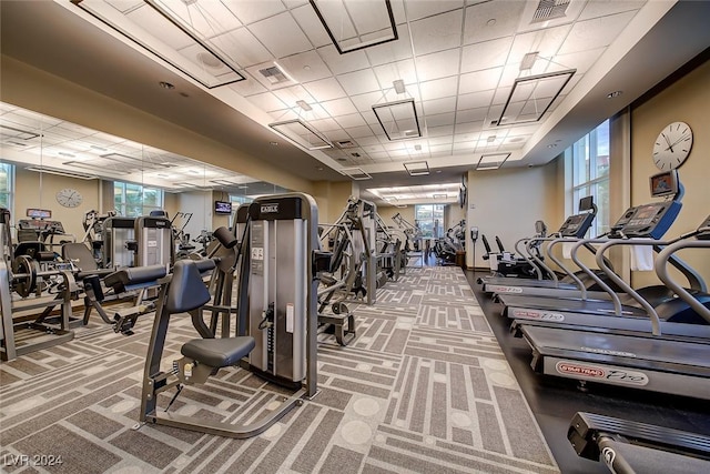 exercise room with a paneled ceiling and carpet flooring