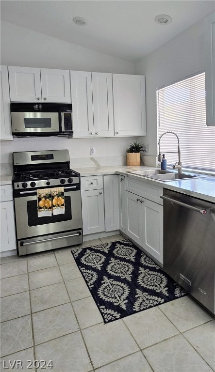 kitchen with appliances with stainless steel finishes, light tile patterned floors, and white cabinets