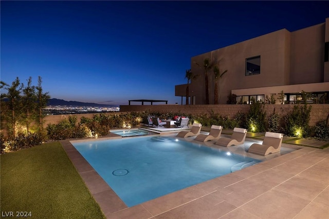 pool at dusk with a mountain view and a patio area