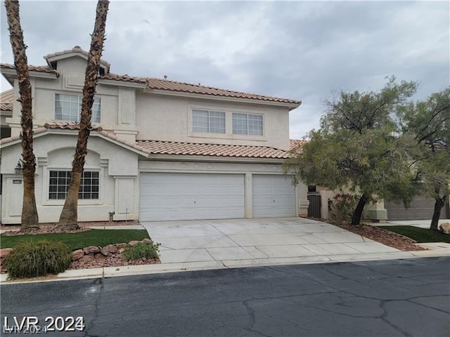 mediterranean / spanish-style home with concrete driveway, a tiled roof, an attached garage, and stucco siding