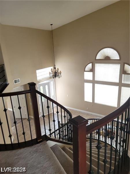 stairs with carpet, a chandelier, and a high ceiling