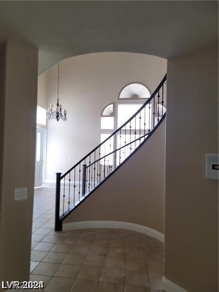 stairs featuring tile patterned floors and an inviting chandelier