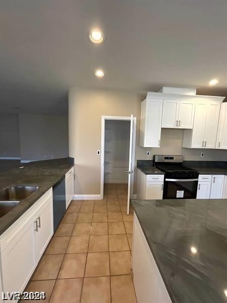 kitchen with light tile patterned flooring, white cabinetry, stainless steel range with electric cooktop, sink, and black dishwasher