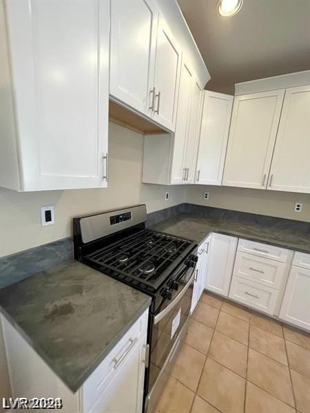 kitchen with white cabinets, light tile patterned floors, and stainless steel gas range oven