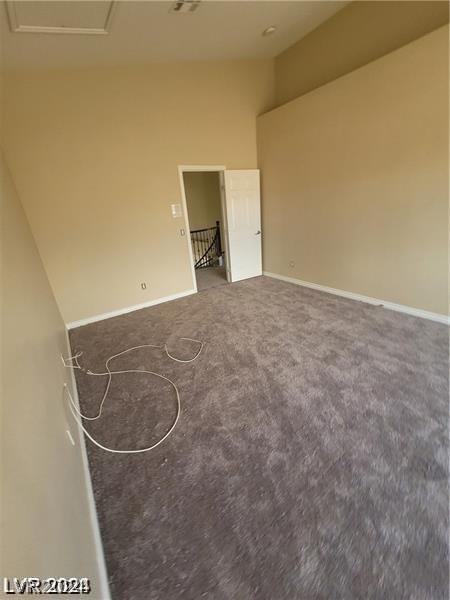 carpeted empty room featuring a towering ceiling