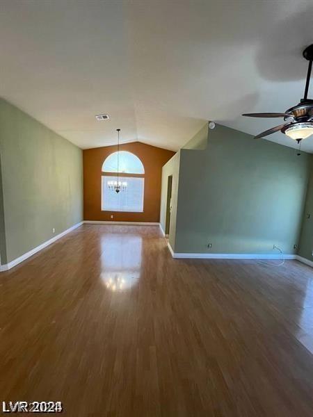 unfurnished living room with visible vents, baseboards, lofted ceiling, and wood finished floors