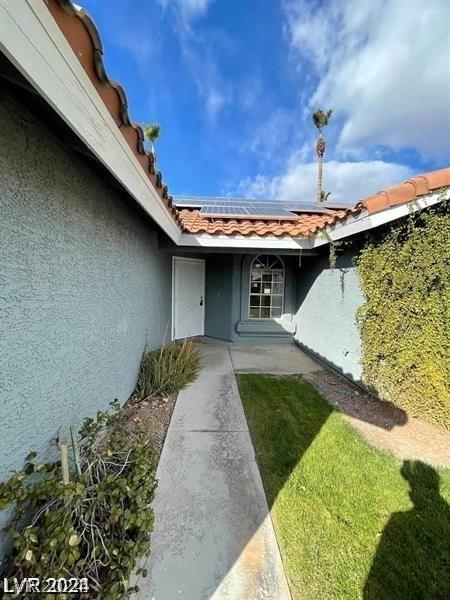 property entrance with stucco siding, roof mounted solar panels, and a tile roof