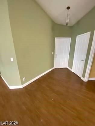 unfurnished dining area featuring vaulted ceiling, wood finished floors, and baseboards