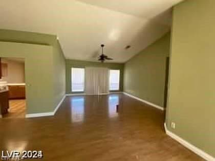 unfurnished living room featuring baseboards, lofted ceiling, a ceiling fan, and wood finished floors