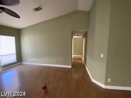 spare room featuring visible vents, baseboards, ceiling fan, vaulted ceiling, and wood finished floors