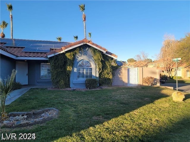 view of front of property with solar panels, a tiled roof, a front lawn, and stucco siding