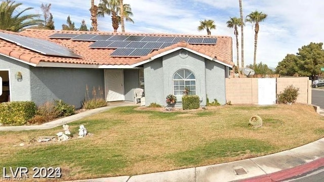 mediterranean / spanish house with stucco siding, solar panels, a front lawn, and a tiled roof