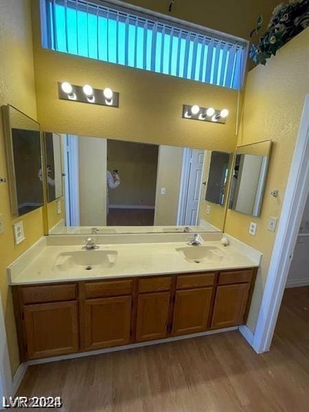 bathroom featuring double vanity, wood finished floors, and a sink