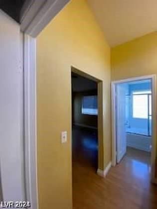 corridor with wood finished floors and vaulted ceiling