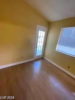 spare room featuring baseboards, lofted ceiling, and wood finished floors