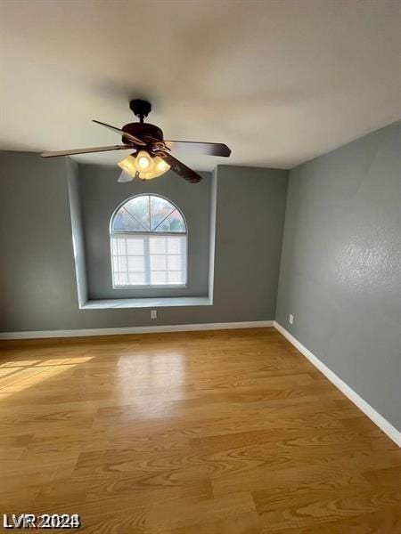 spare room featuring ceiling fan, baseboards, and wood finished floors