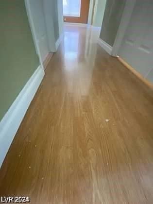 hall with baseboards and wood finished floors