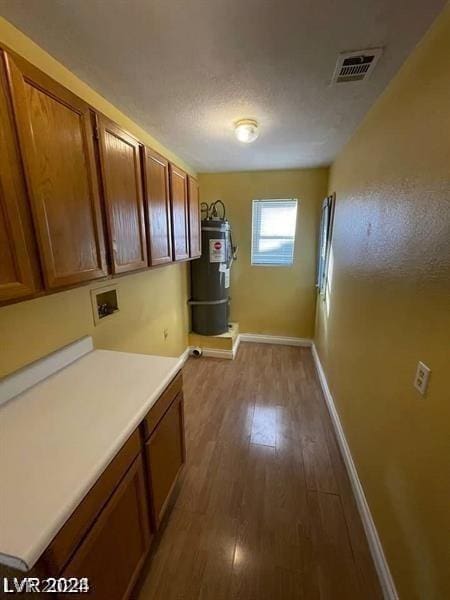 interior space featuring visible vents, brown cabinets, wood finished floors, and water heater