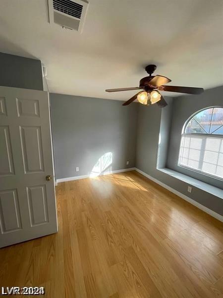 empty room with visible vents, ceiling fan, baseboards, and light wood-style floors