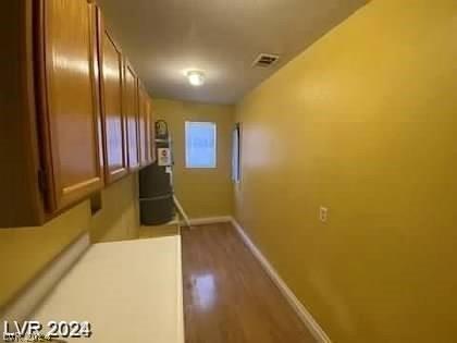 hallway with visible vents, baseboards, and wood finished floors