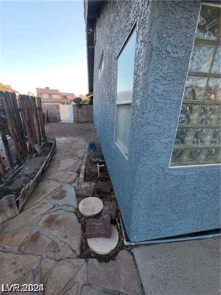 view of side of property featuring stucco siding, a patio area, and fence