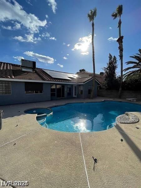 view of pool featuring cooling unit, a pool with connected hot tub, and a patio