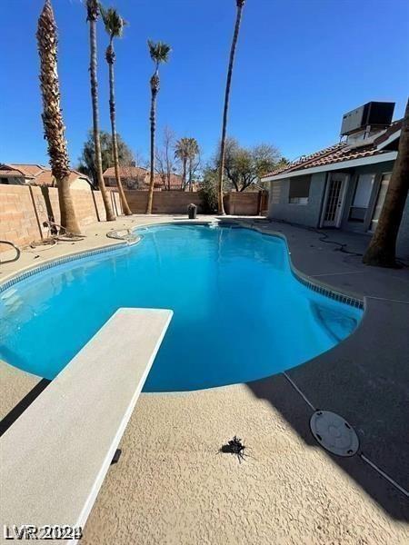 view of pool featuring a diving board, a fenced in pool, central AC, and a fenced backyard