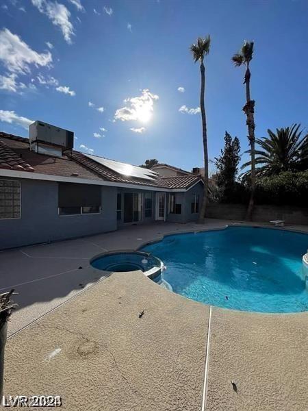 view of swimming pool with central AC unit, a pool with connected hot tub, and a patio