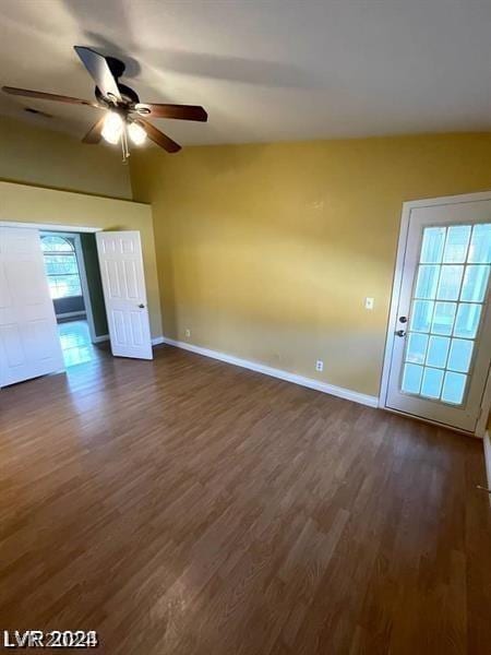 spare room with a ceiling fan, lofted ceiling, baseboards, and dark wood-style flooring