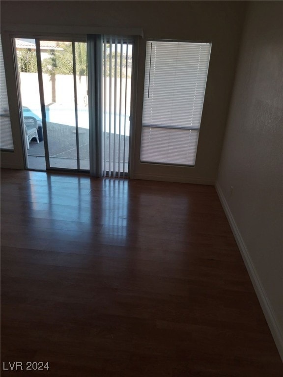 spare room with baseboards and dark wood-type flooring