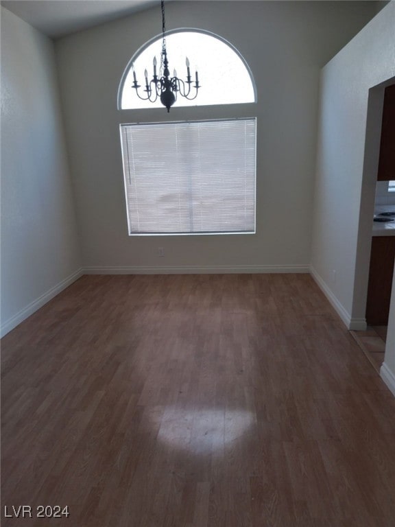 unfurnished dining area with baseboards, wood finished floors, and a chandelier