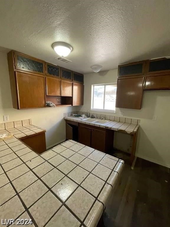 kitchen featuring tile counters, sink, and a textured ceiling