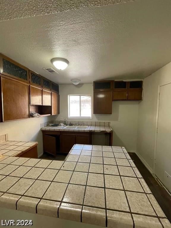 kitchen featuring tile counters and a textured ceiling