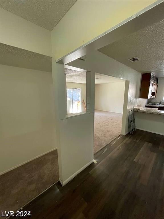 hall featuring dark colored carpet and a textured ceiling