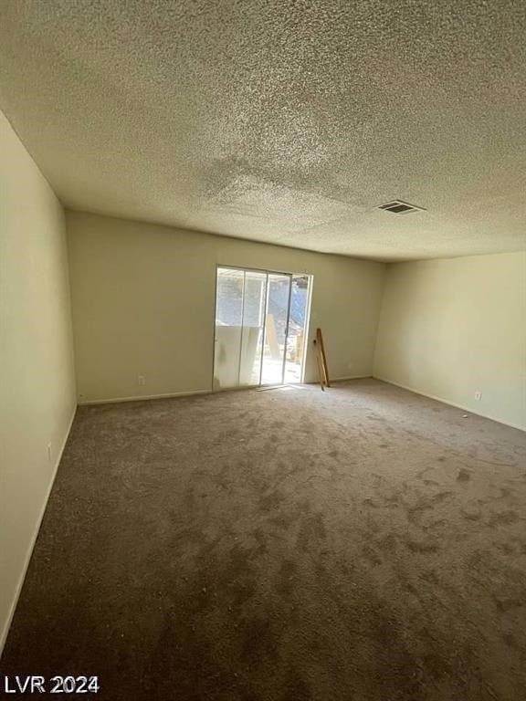 carpeted empty room with a textured ceiling