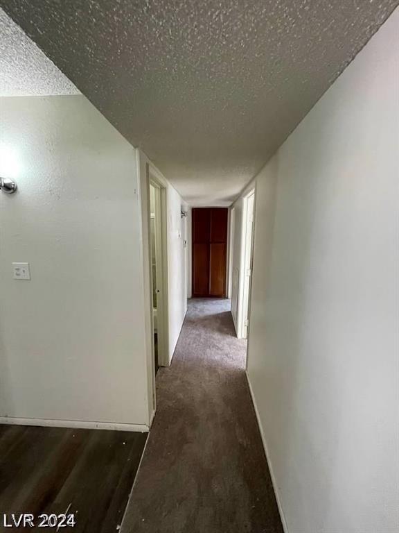 hall with dark hardwood / wood-style flooring and a textured ceiling