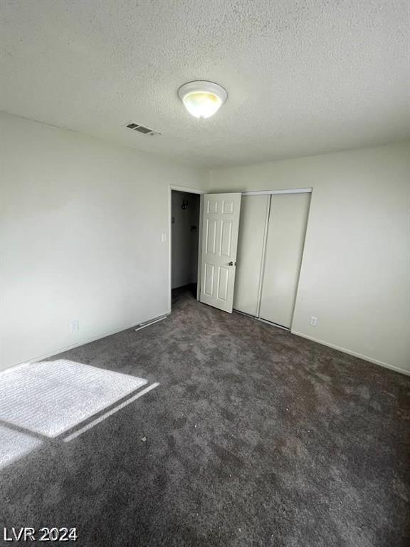 unfurnished bedroom featuring a closet, carpet flooring, and a textured ceiling