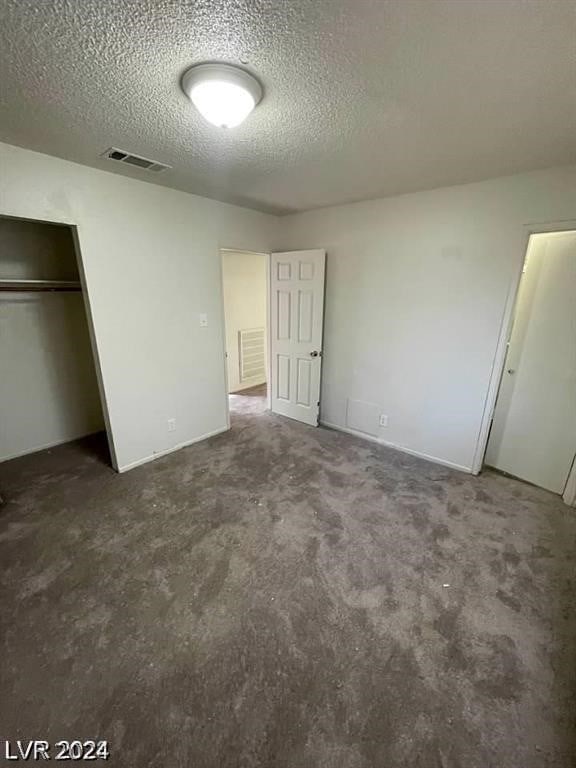 unfurnished bedroom featuring a closet, a textured ceiling, and carpet floors